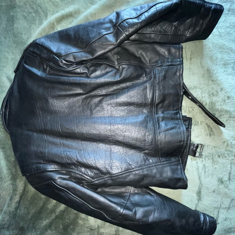 size large, heavy black leather jacket with shoulder pads, a buckle, & 4 pockets